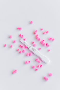 白色表面上的妊娠试验呈阳性，上面散布着粉红色的棒棒糖
