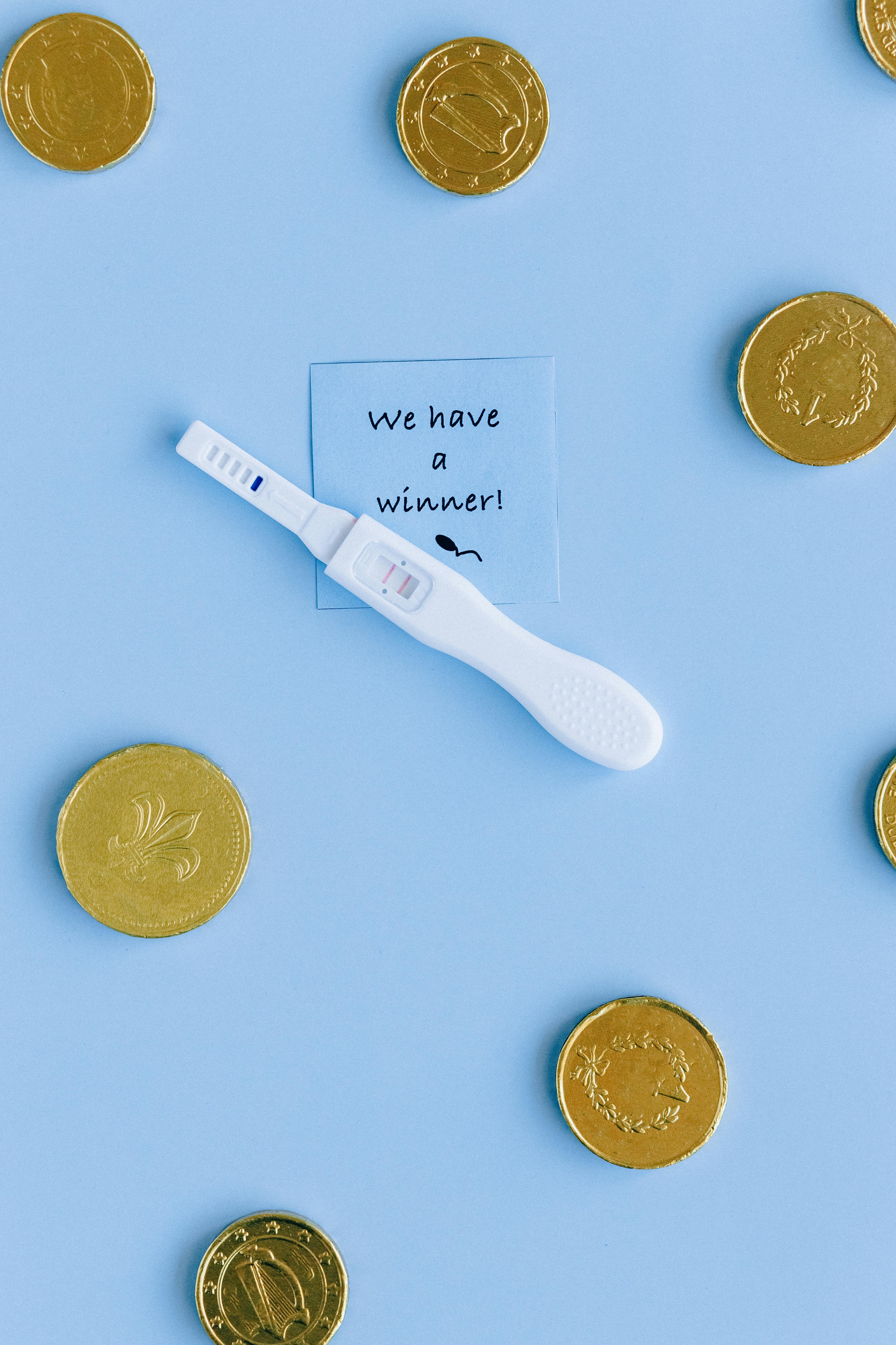 white pregnancy test kit with two gold coins