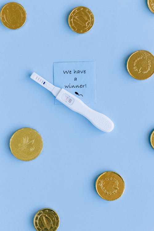 White Pregnancy Test Kit With Two Gold Coins