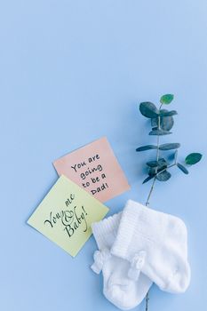蓝色背景上，婴儿袜点缀着创意平坦的怀孕公告笔记