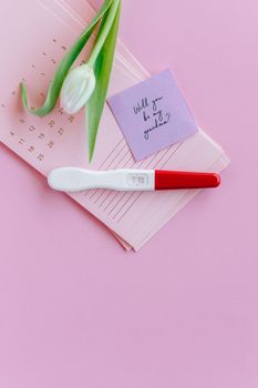 日历上，白色郁金香旁的妊娠测试呈阳性，象征着希望和期待