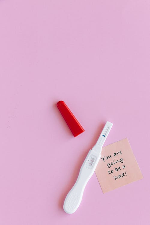 
A Pregnancy Test and a Sticky Note on a Pink Surface
