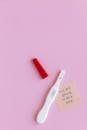 A Pregnancy Test and a Sticky Note on a Pink Surface
