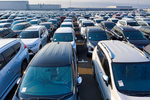 Rows of many contemporary expensive automobiles parked on asphalt of manufacture in daytime