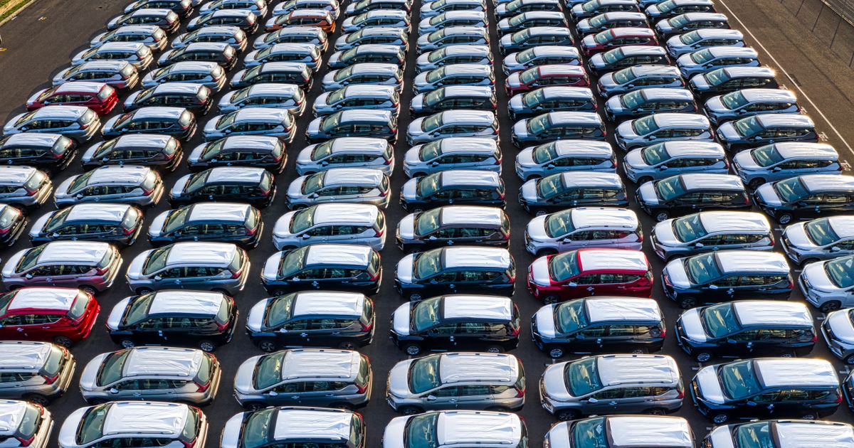 Aerial view of rows of new cars in a large lot.