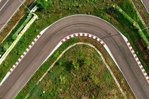 Drone view of narrow modern asphalt road near ground with fresh verdant grass