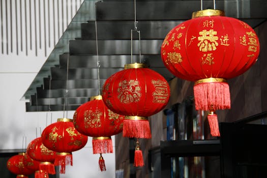 A close-up of red Chinese lanterns, adorned with gold symbols, hanging outdoors.