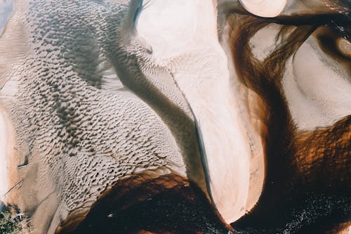 Sandy dunes washing by waving sea in sunlight