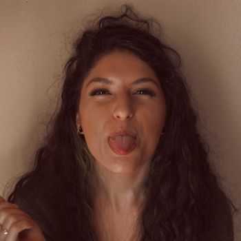 Portrait of a playful woman sticking out her tongue with messy curly hair indoors.