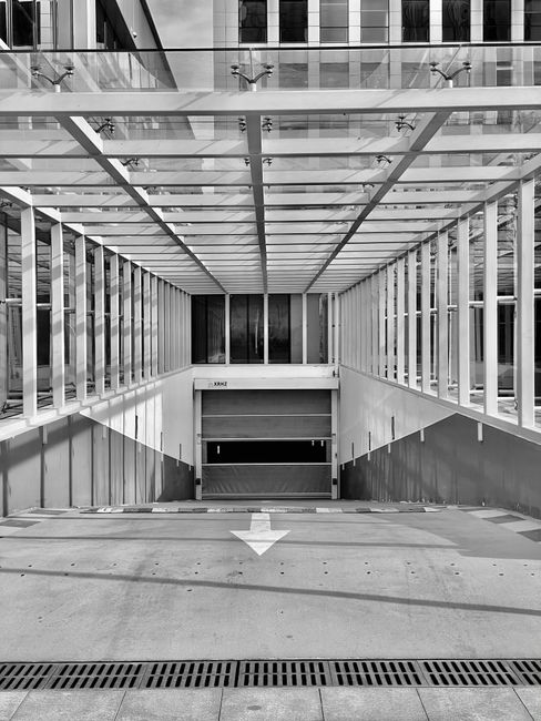 Symmetrical entrance to an underground parking lot with modern glass architecture.