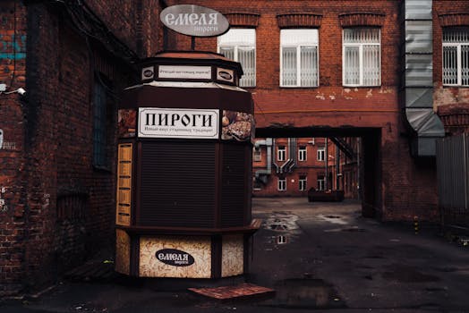 A closed street food stand in an industrial district with brick buildings and windows. Moody atmosphere.