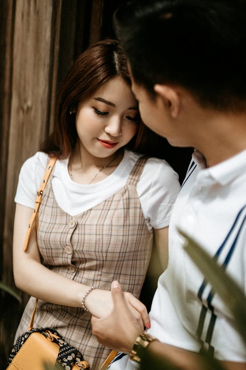 Free Happy Asian couple in summer clothes holding hands together and smiling while spending weekend Stock Photo