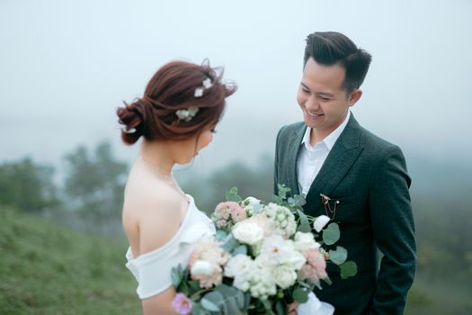 一对亚洲夫妇迷人的户外婚礼照片，拥抱爱与自然