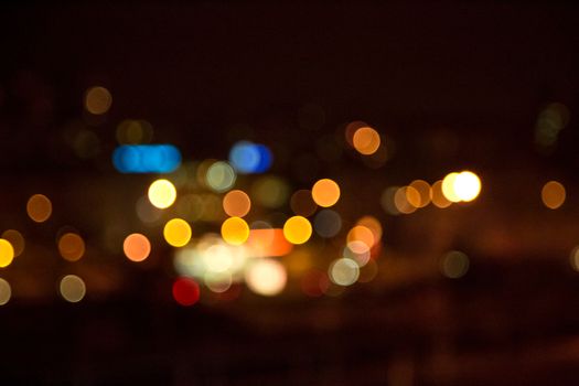 Blurred city lights at night create a colorful bokeh effect, capturing an urban ambiance.