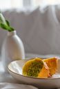 Fresh cut jelly melon with spiny peel in ceramic bowl near vase with plant stem on creased textile