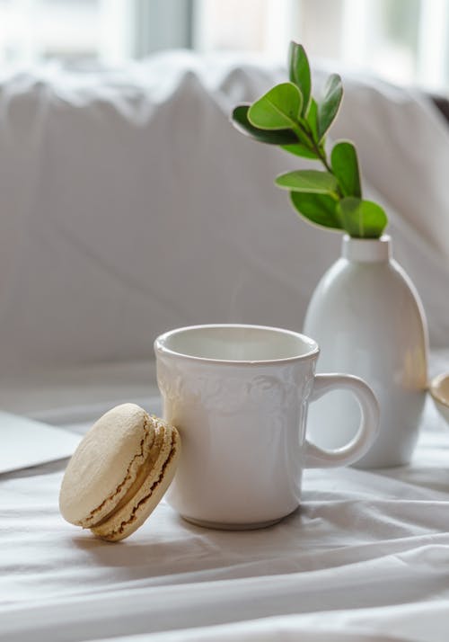 Ceramic mug and delicious macaroon on creased fabric