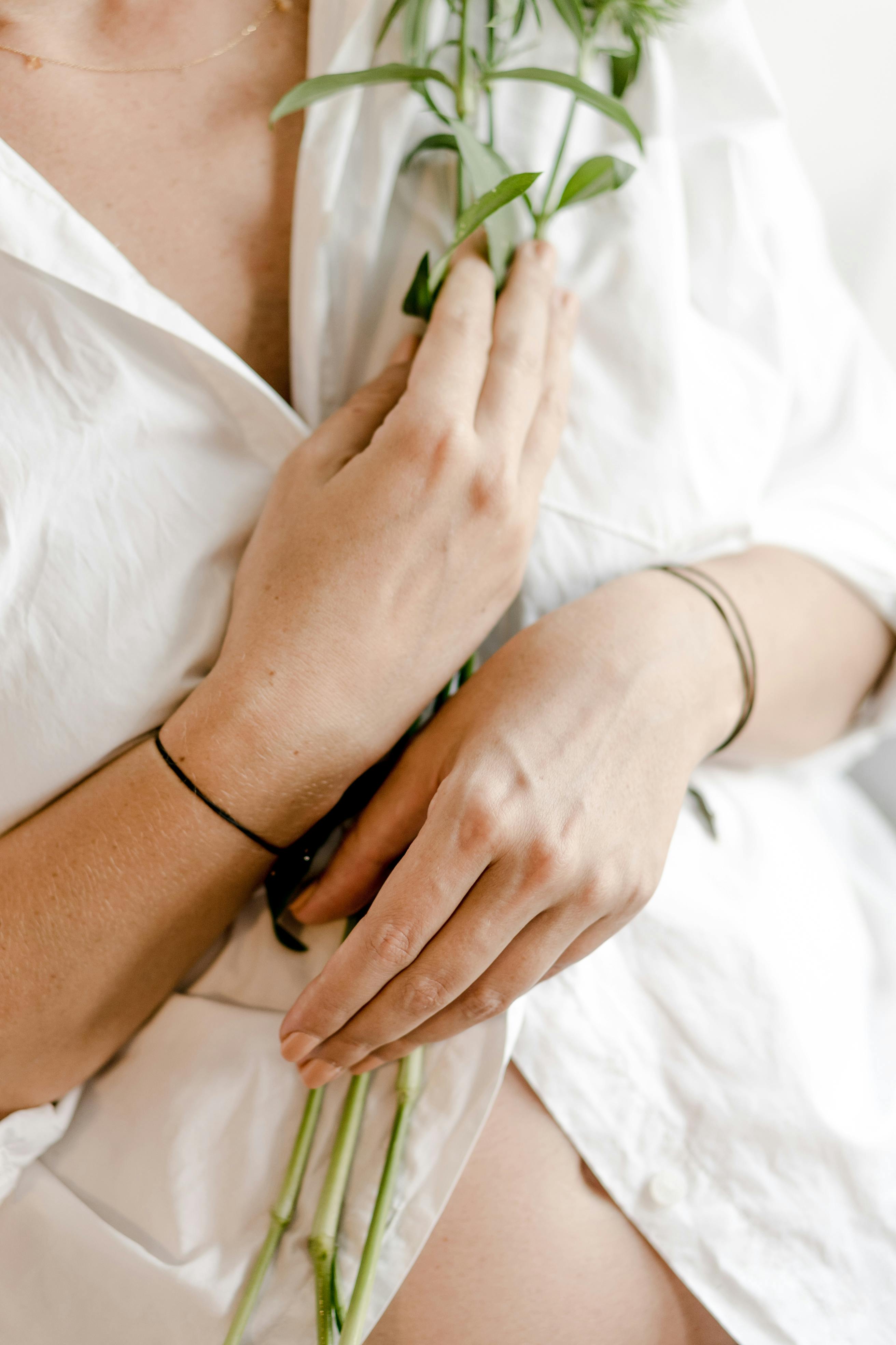 faceless expectant woman in white apparel with plant stems