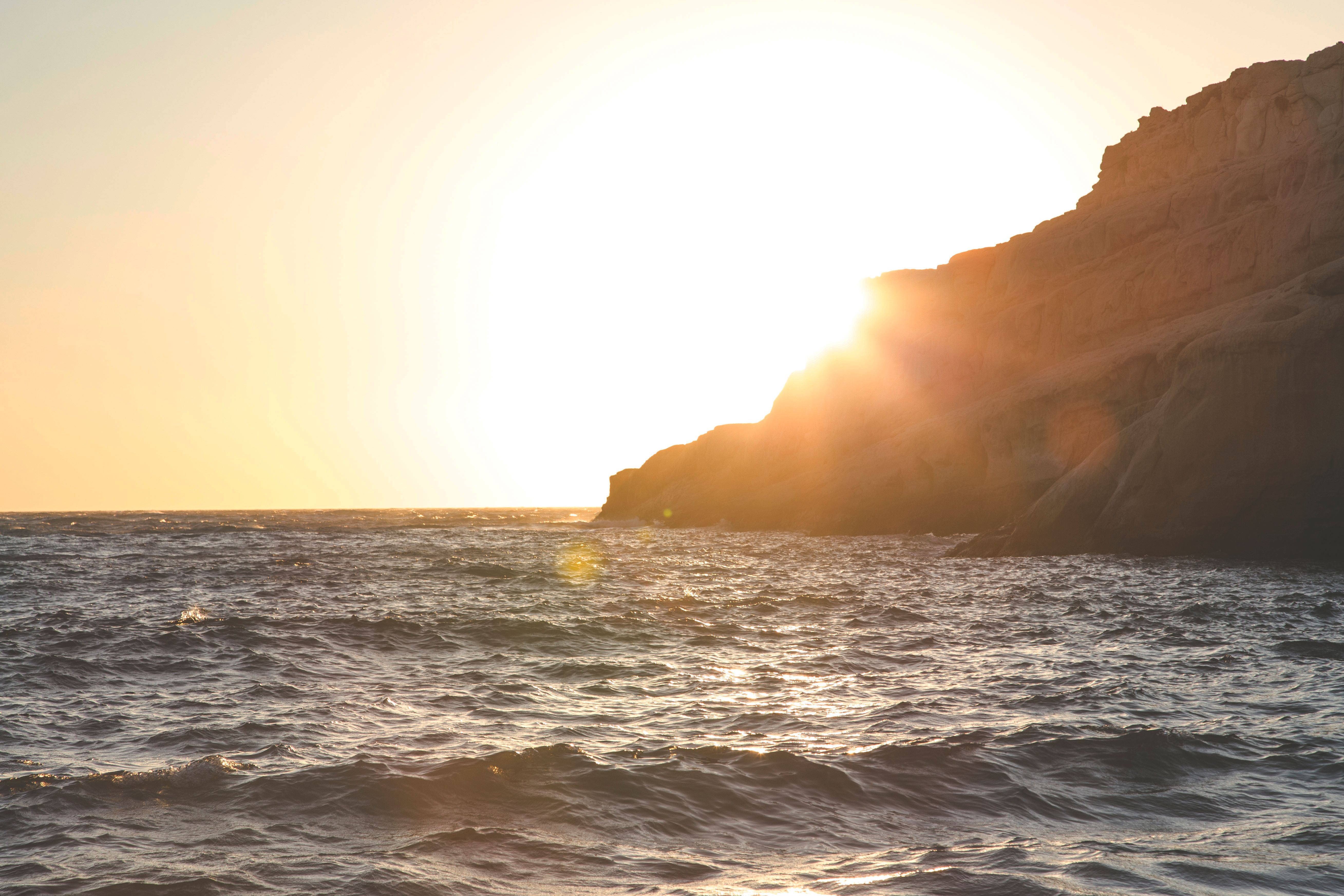 Rocky cliff washed by waving sea in evening · Free Stock Photo
