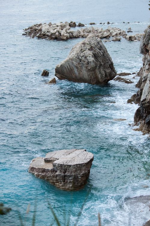 Free Scenery of rough rocks scattered in shallow azure seawater rippling near rough coast on clear weather Stock Photo