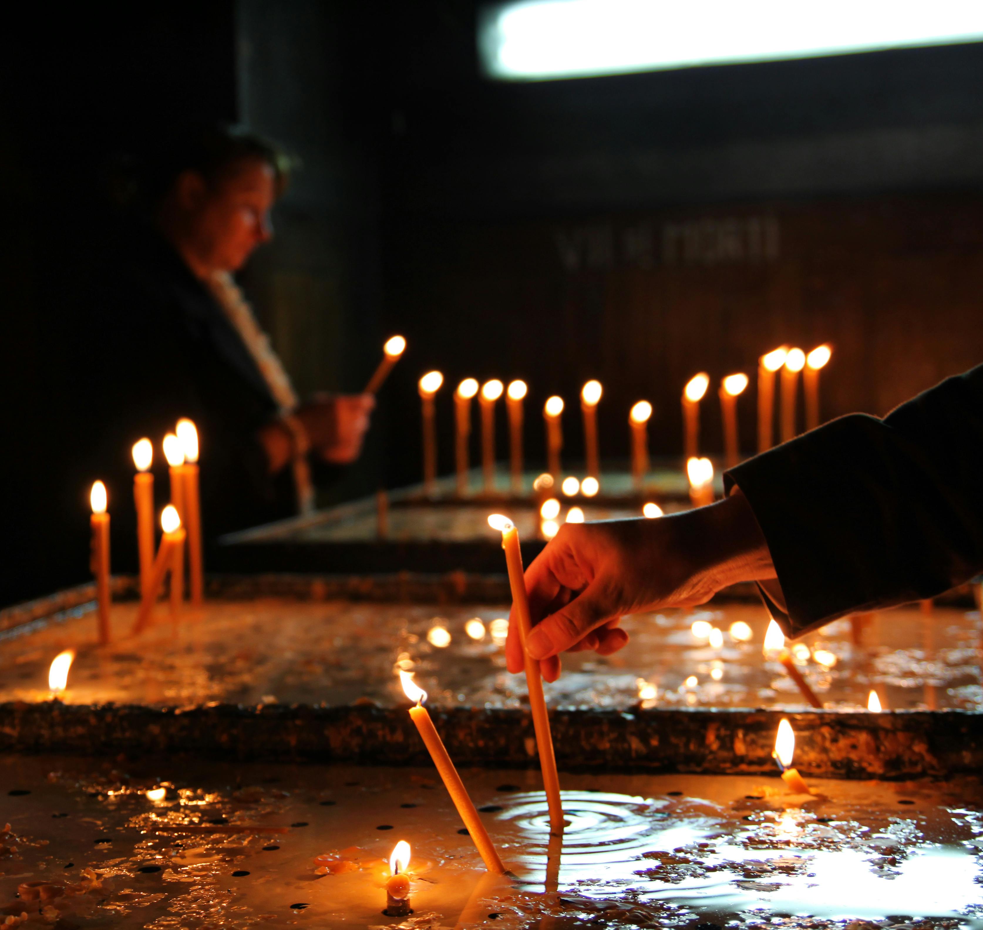 crop person putting candle in church