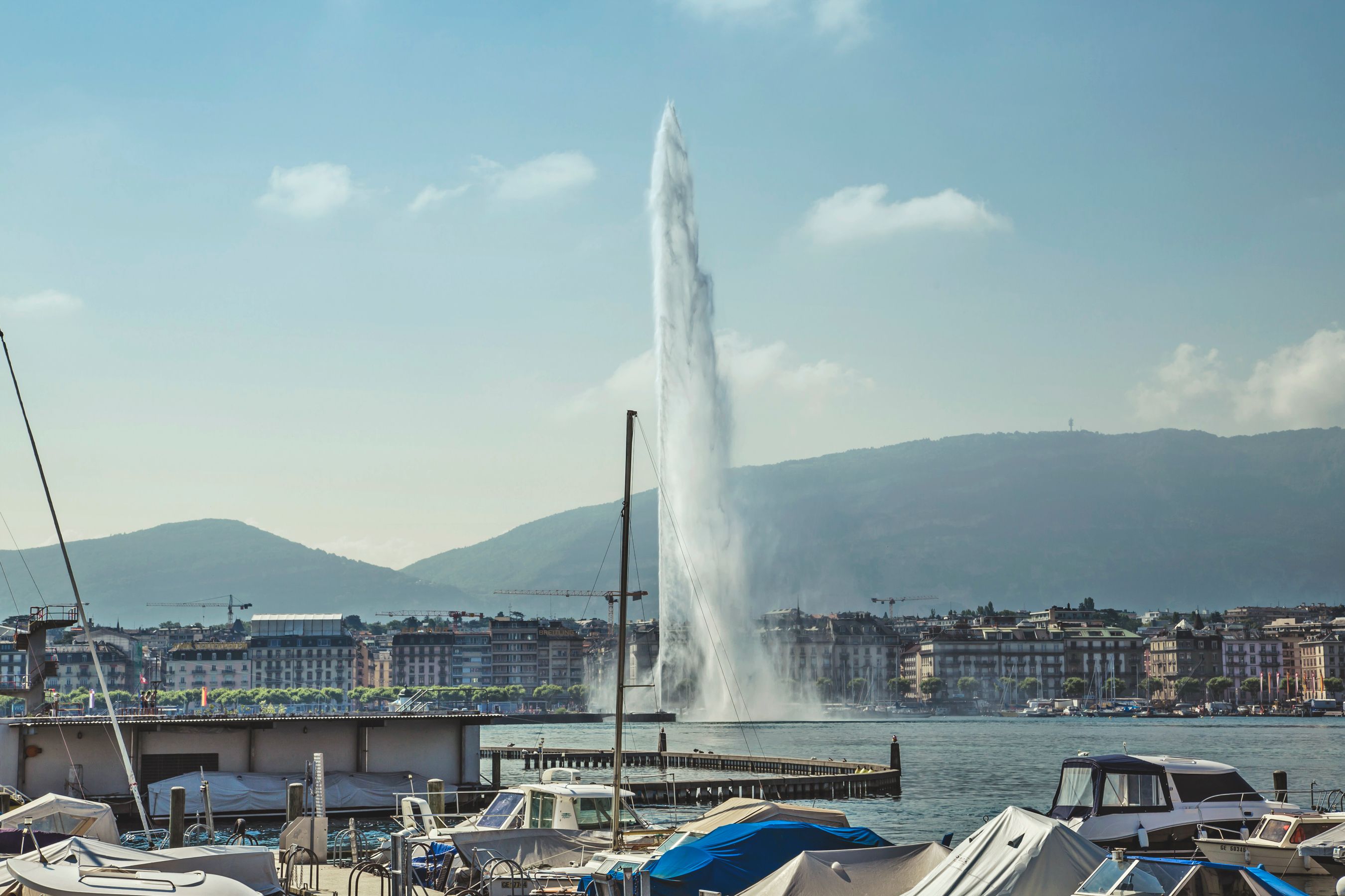 Best lakefront hotels in Geneva — mountains behind city with Jet d'Eau on embankment of Lake Geneva