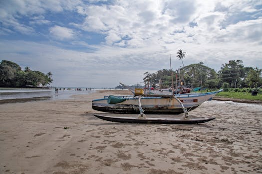 Shabby motorboat on sandy coast of rippling ocean water in tropical country under blue sky with clouds