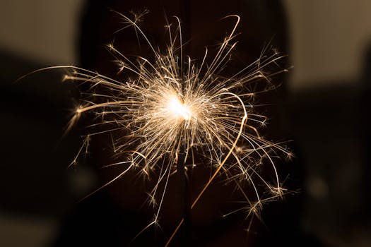 Closeup of thin glowing flame of burning sparkler in dark room at night