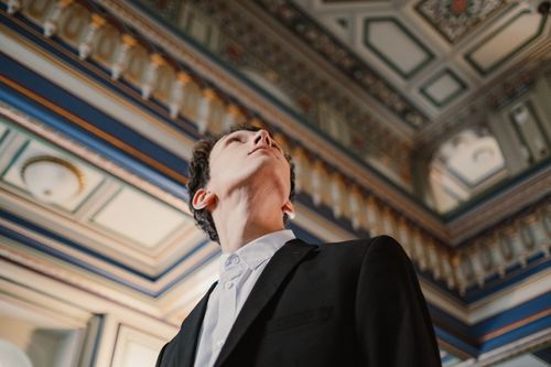 Free A well-dressed man looking up at an ornate indoor ceiling, showcasing classic architectural details. Stock Photo