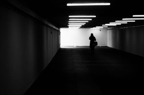 Free Silhouette of a person walking in a dimly lit underpass creating a moody atmosphere. Stock Photo
