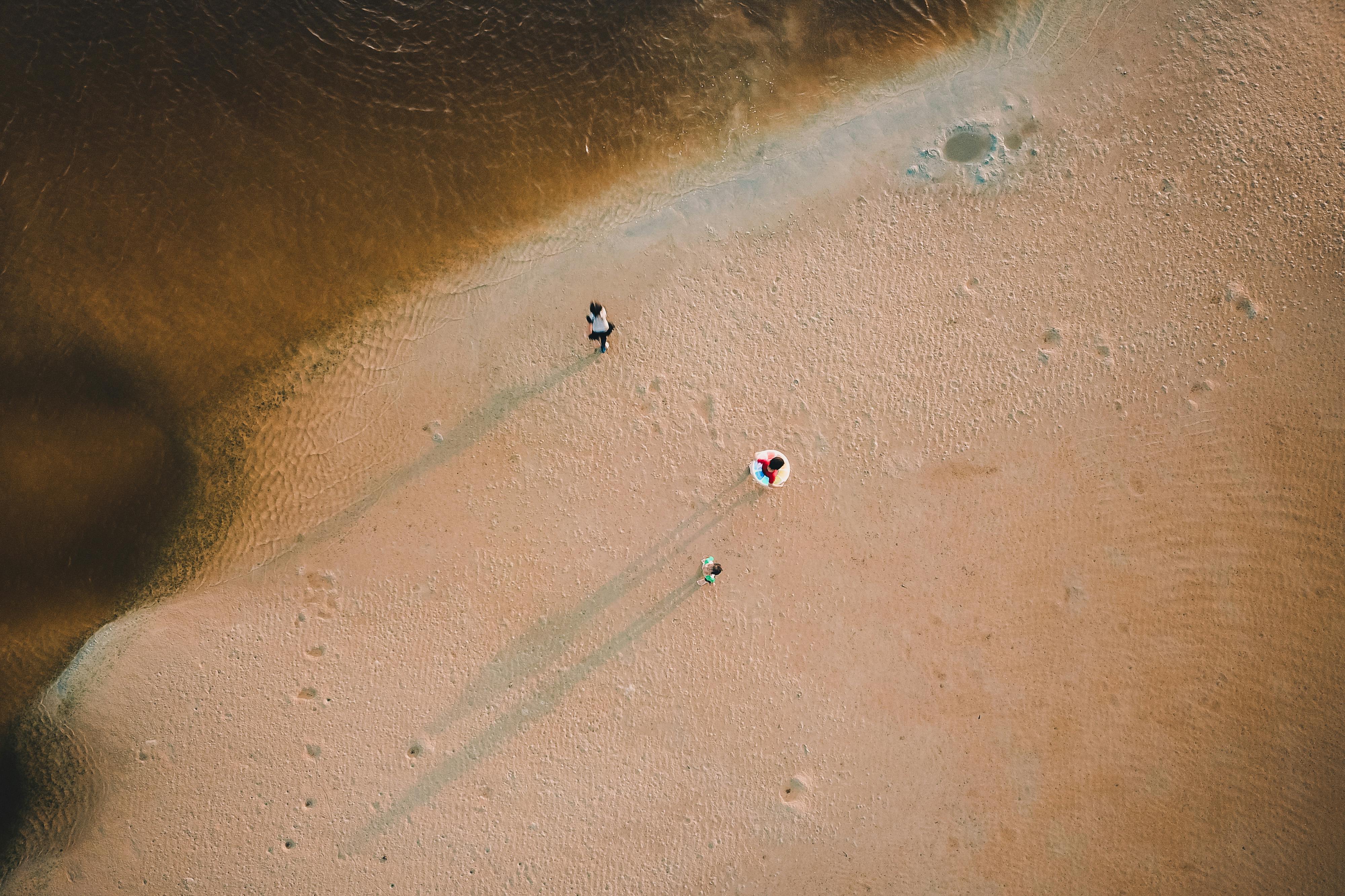A drone captures people enjoying a serene beach with clear waters and golden sand.
