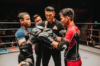 拳击台上，两名拳击手和一名裁判在激烈的战斗开始前严阵以待