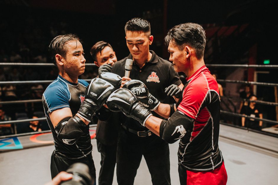 Two boxers and a referee engage in an intense pre-fight moment in the boxing ring. — photo by Coco Championship