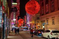 People Walking on Sidewalk With Red Heart Balloon