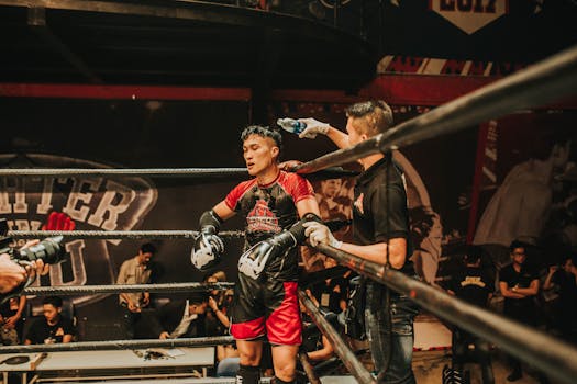 A boxer receives coaching during an intense match in a bustling arena.