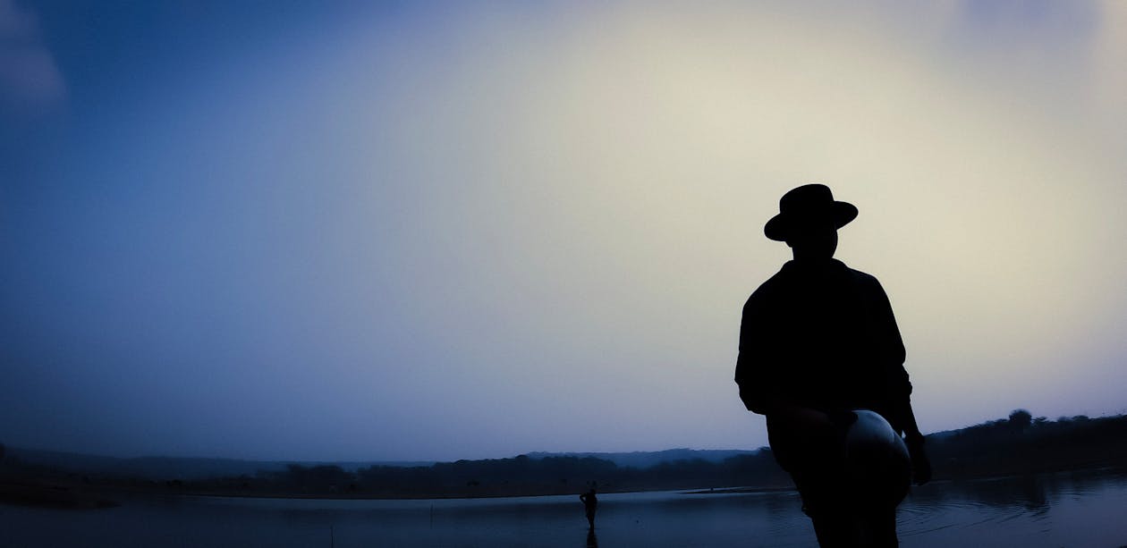 Free Silhouette of Man Standing Near Body of Water Stock Photo
