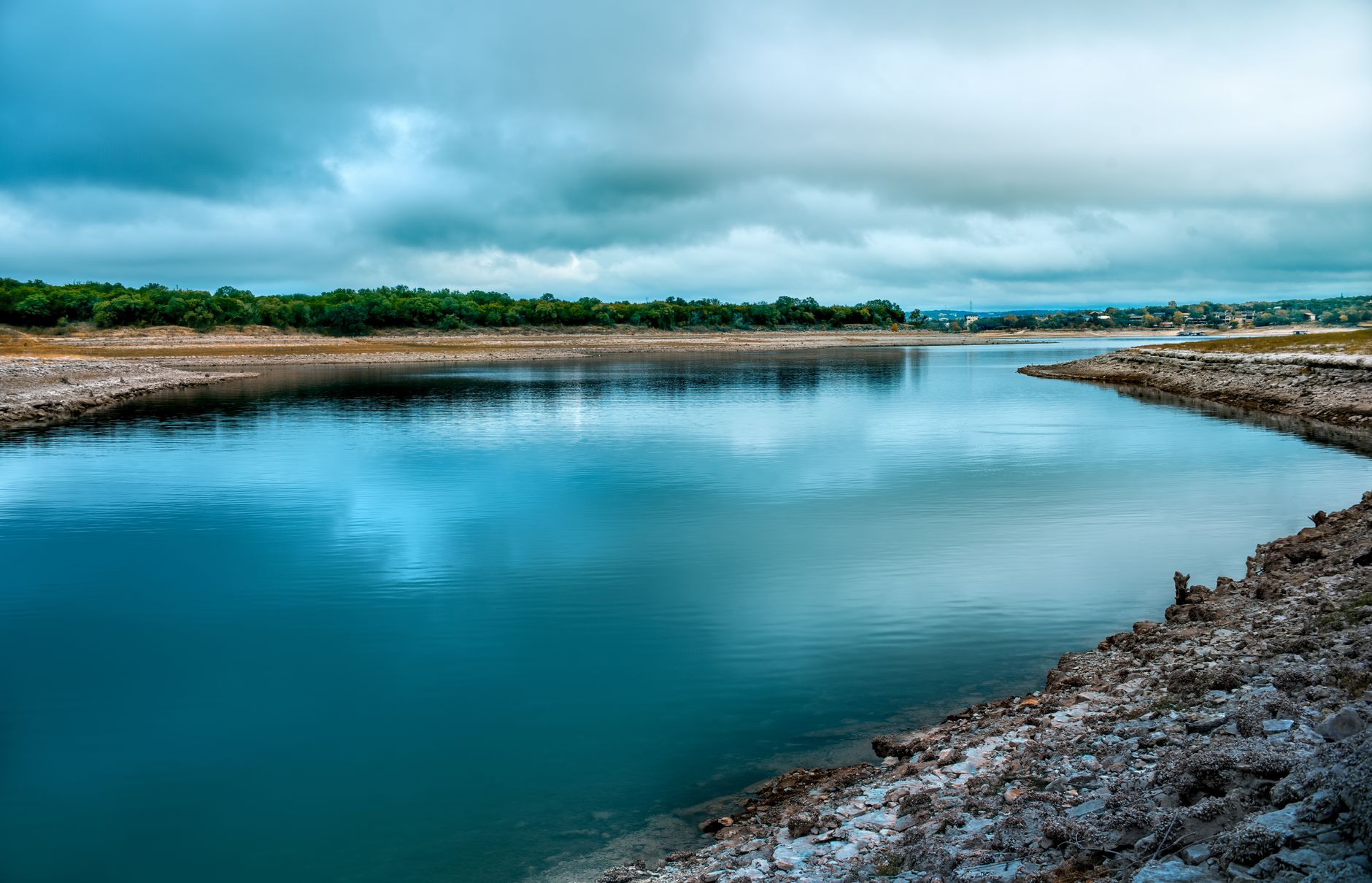 Calm river reflecting a moody, cloudy sky with a beautiful natural landscape in Texas.