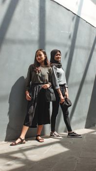 Two young women stylishly posing in an urban setting, capturing modern fashion vibes.