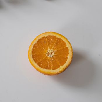 将切成半的新鲜成熟橙子放在白色桌子上