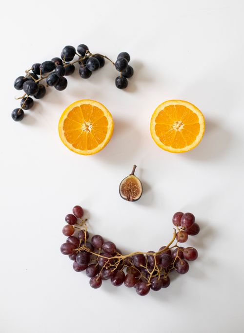 Free From above arrangement of fresh cut orange and ripe fig with bunches of grapes composed as smiling face with big eyes Stock Photo