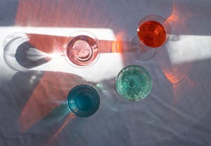 Top view of transparent glasses filled with different beverages and placed at sun beam