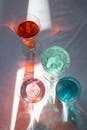 From above of crystal glasses filled with refreshing drinks on white table in sunlight
