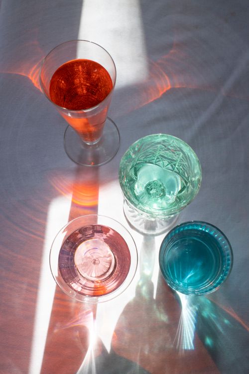 Free From above of crystal glasses filled with refreshing drinks on white table in sunlight Stock Photo