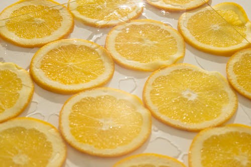 Closeup background of fresh juicy orange slices arranged on white surface with clear ice