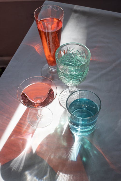 Crystal glassware filled with alcohol beverages and served on table with white tablecloth in daylight
