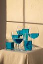 Arrangement of transparent glasses filled with blue drink and placed on table with white tablecloth