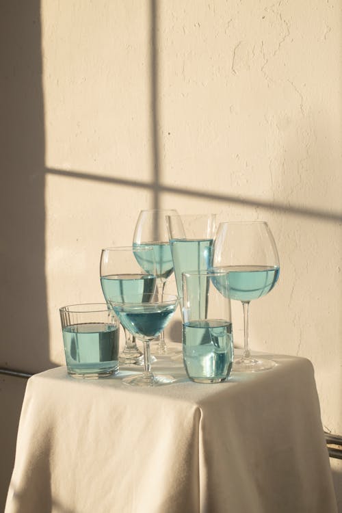 Set of various glasses filled with blue drink and placed on table