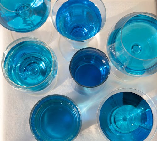 Top view of various glasses filled with colorful drinks in different blue color shades