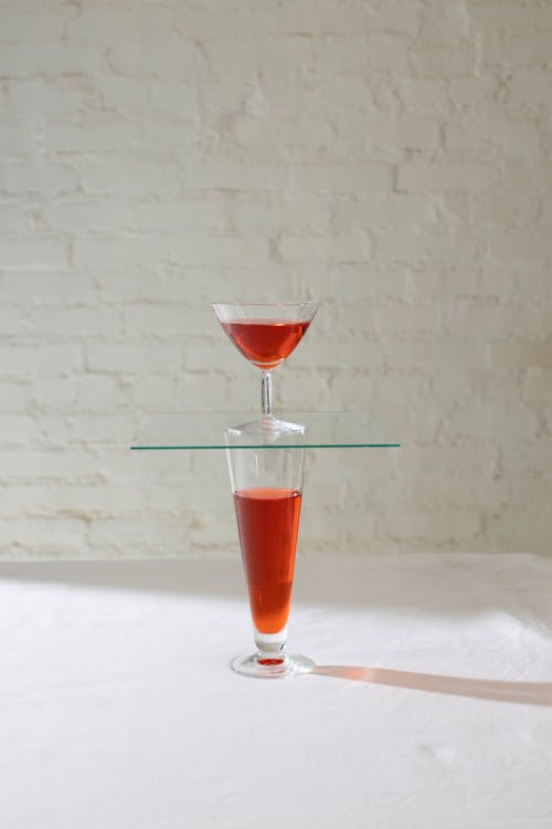 Glasses with red alcoholic drink standing on each other placed on white table