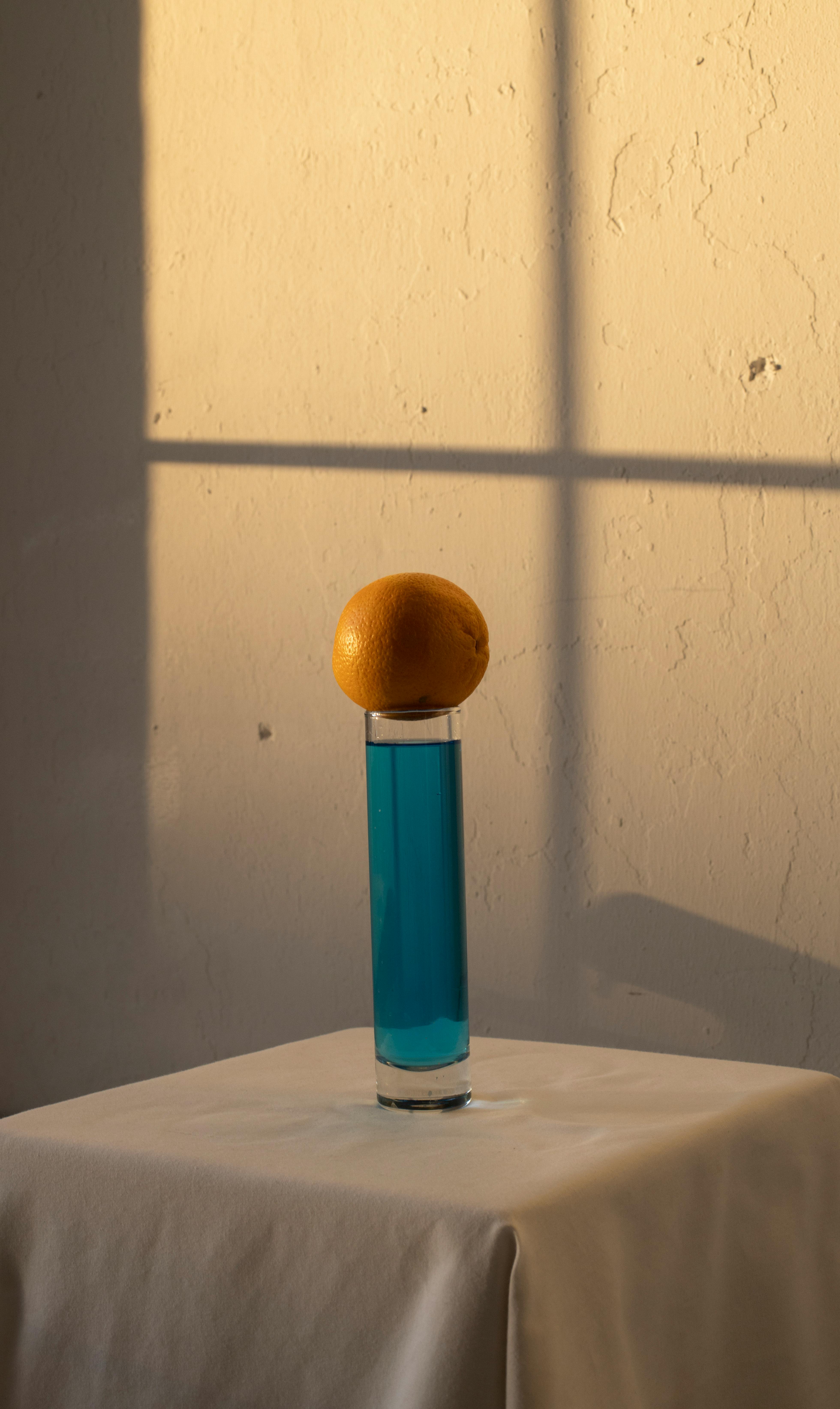 orange placed above glass with blue drink