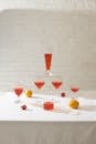 Crystal glasses with red drink composed with oranges and pink flowers on white tablecloth